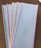 White blank cross-stitch bookmarks with green, red, yellow, orange and pink stitched borders
